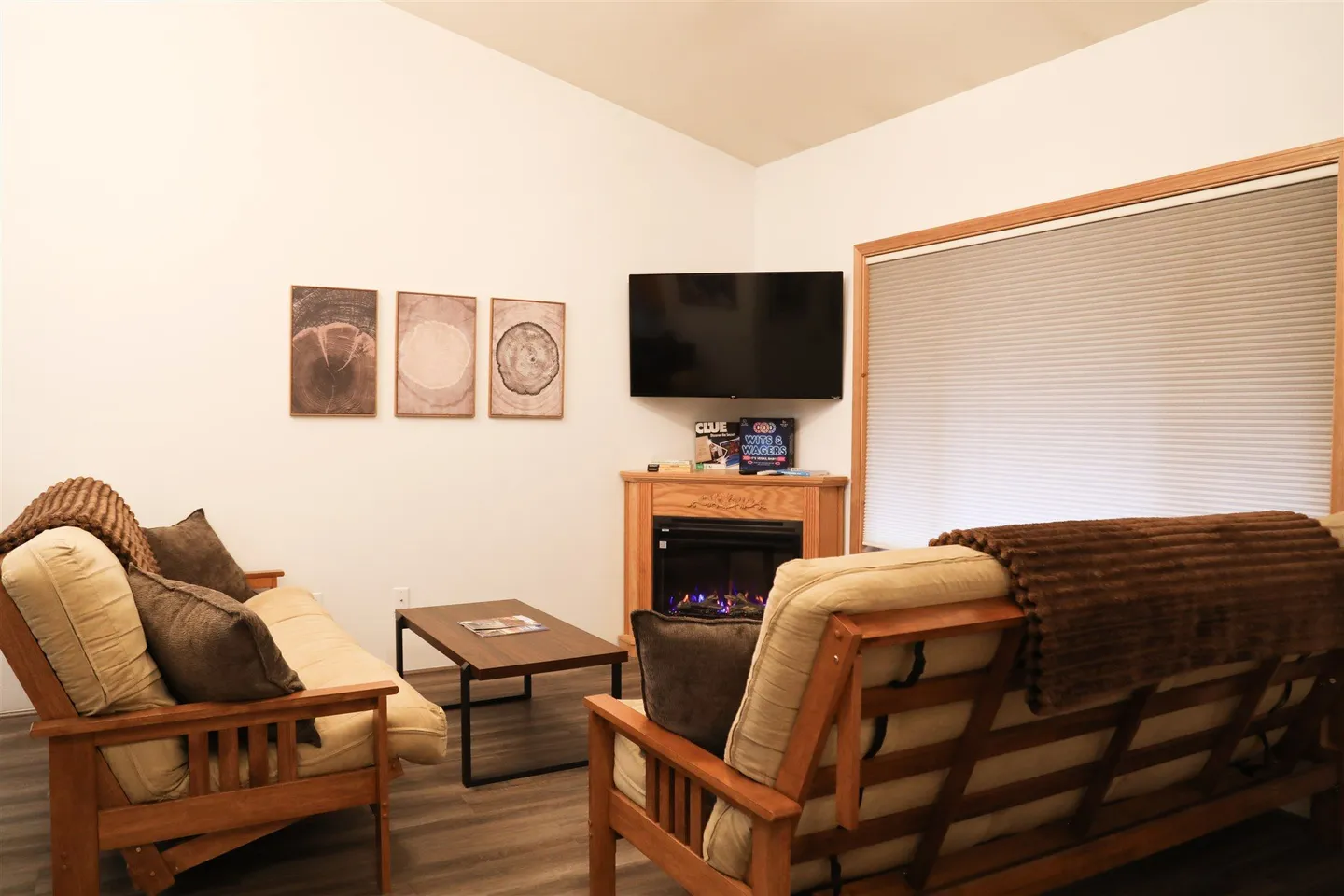 Living area featuring two wooden-framed sofas with cushions, a coffee table, a corner fireplace, and a wall-mounted TV.