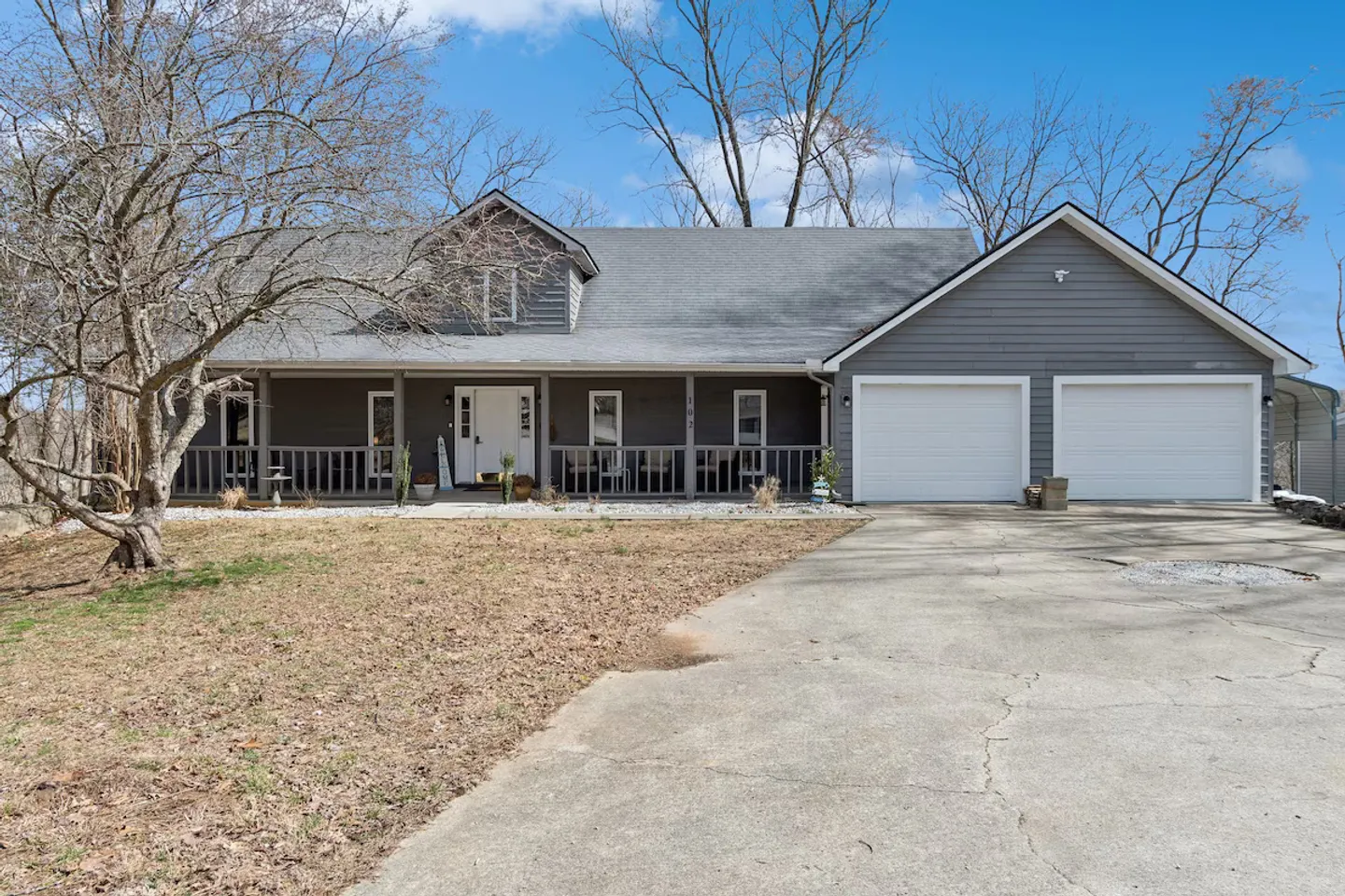 Front exterior of a gray single-family home with a two-car garage, covered front porch, and concrete driveway.