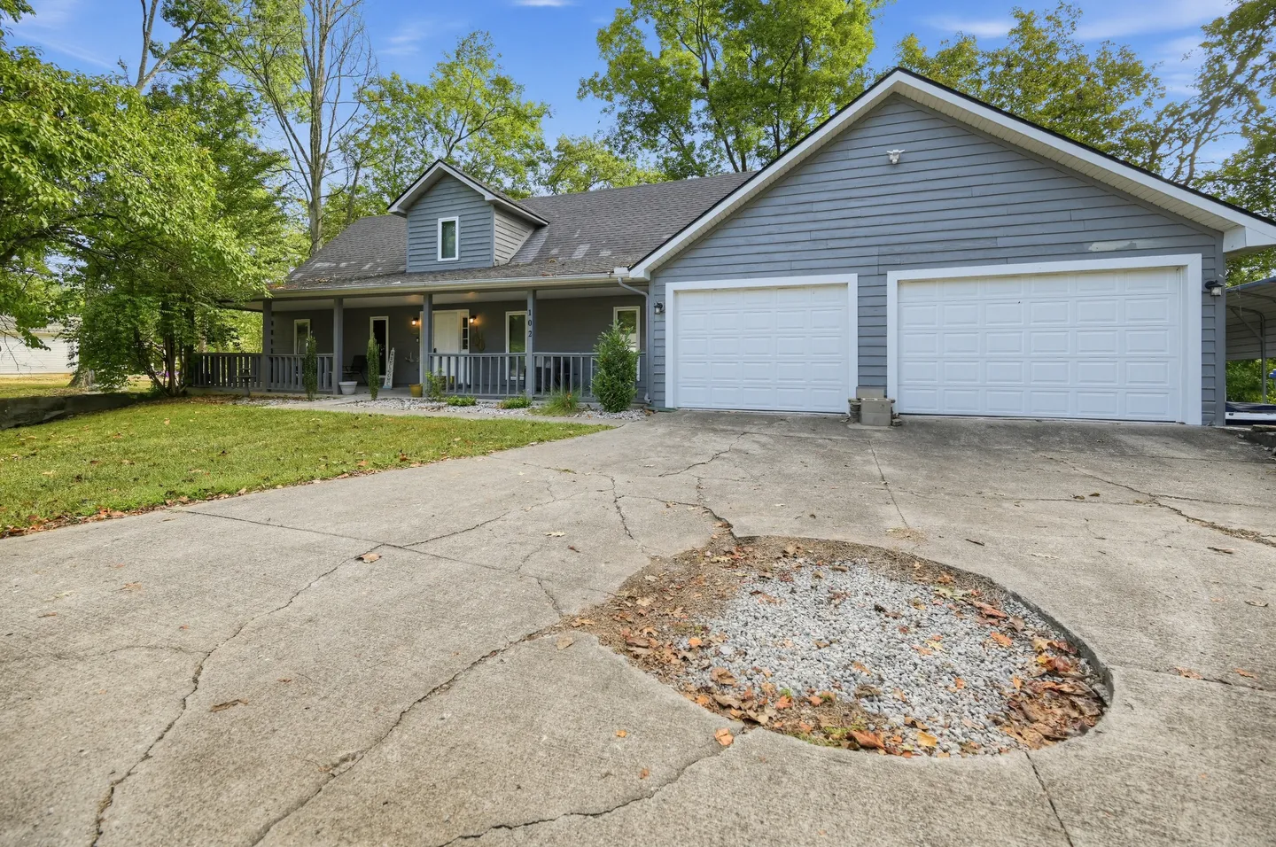 Exterior front view of a grey siding home with an attached two-car garage, front porch, and concrete driveway.