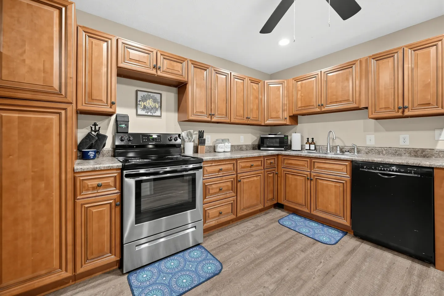 Kitchen with wooden cabinetry, laminate countertops, a stainless steel range, and a black dishwasher.