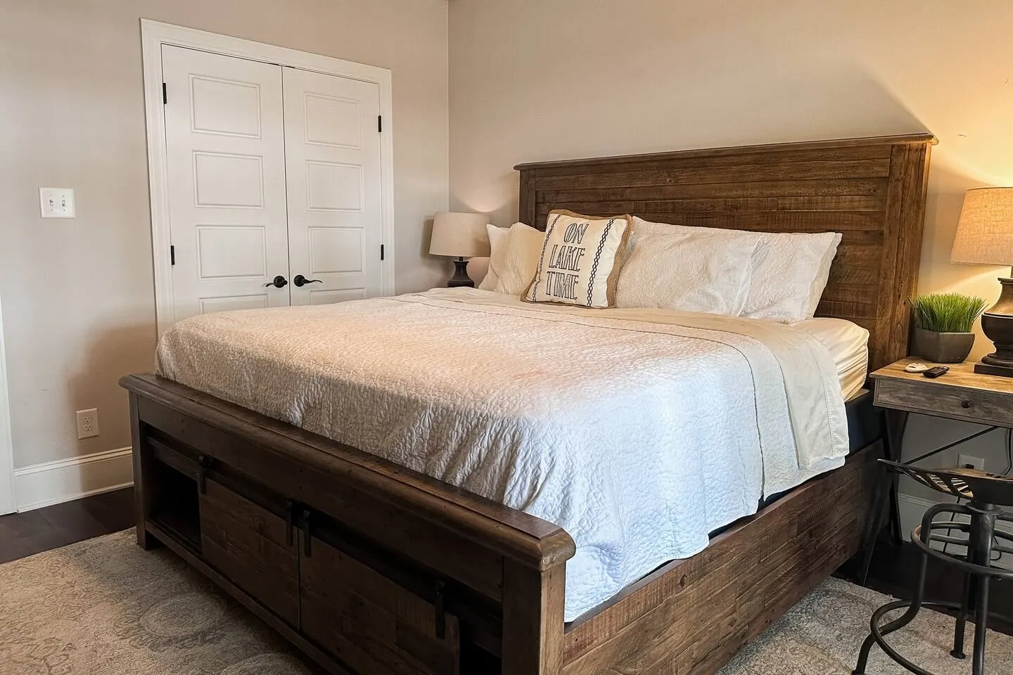Bedroom featuring a dark rustic wood bed frame with storage drawers, dressed in white bedding with an accent pillow.
