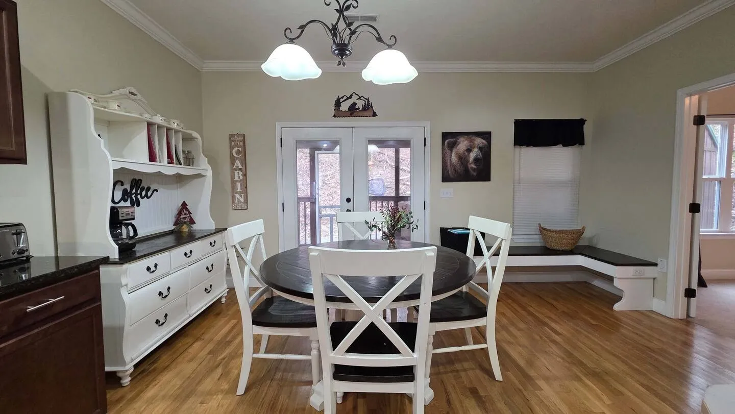 Dining area with a round dark wood table, white chairs, a large white hutch, and French doors leading outside.