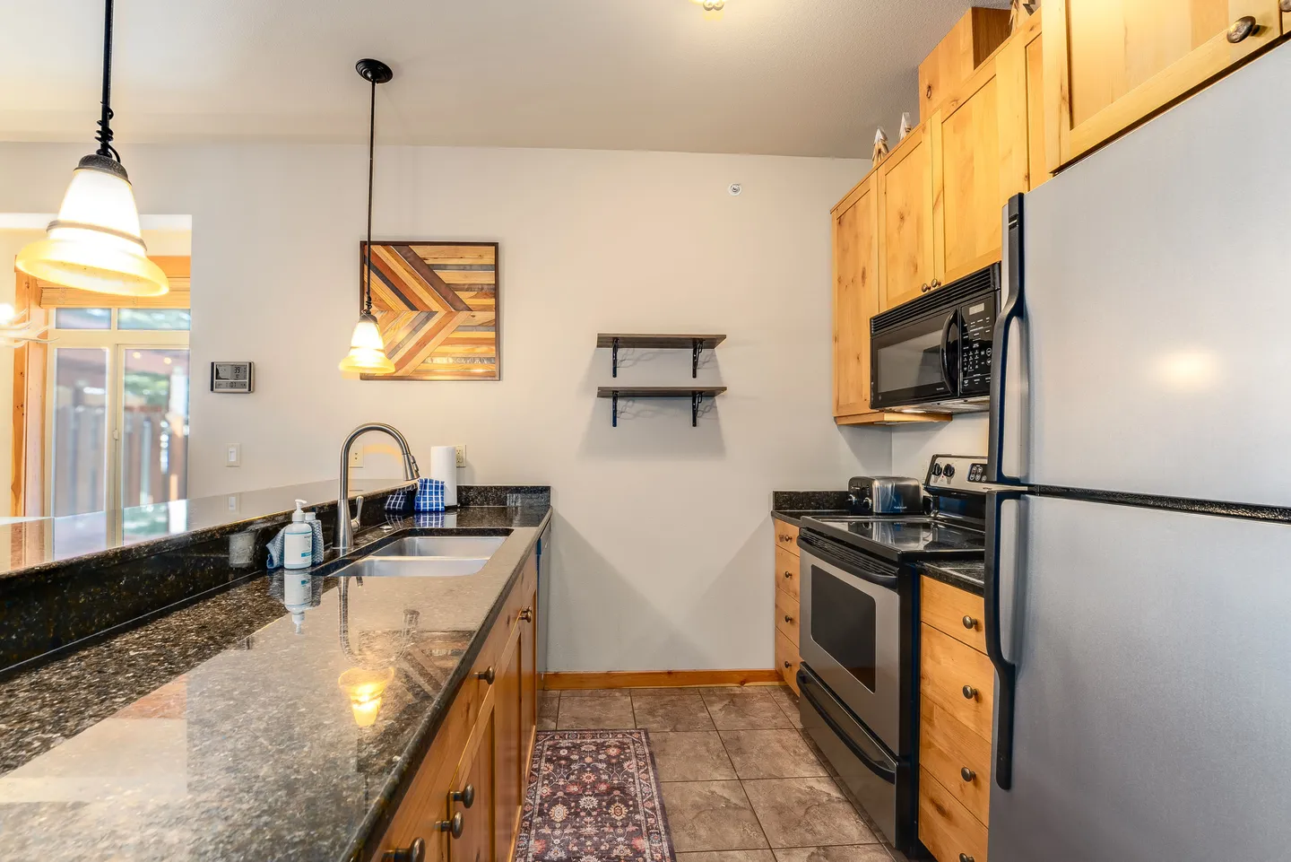 Kitchen with dark granite countertops, light wood cabinets, and stainless steel appliances.