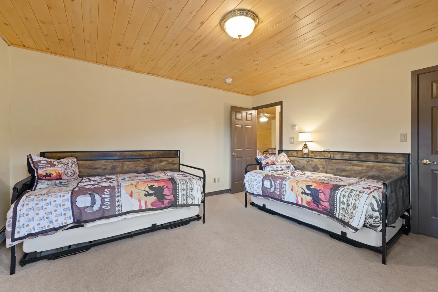 Bedroom with two daybeds featuring trundles, carpeted flooring, and a wood-paneled ceiling.