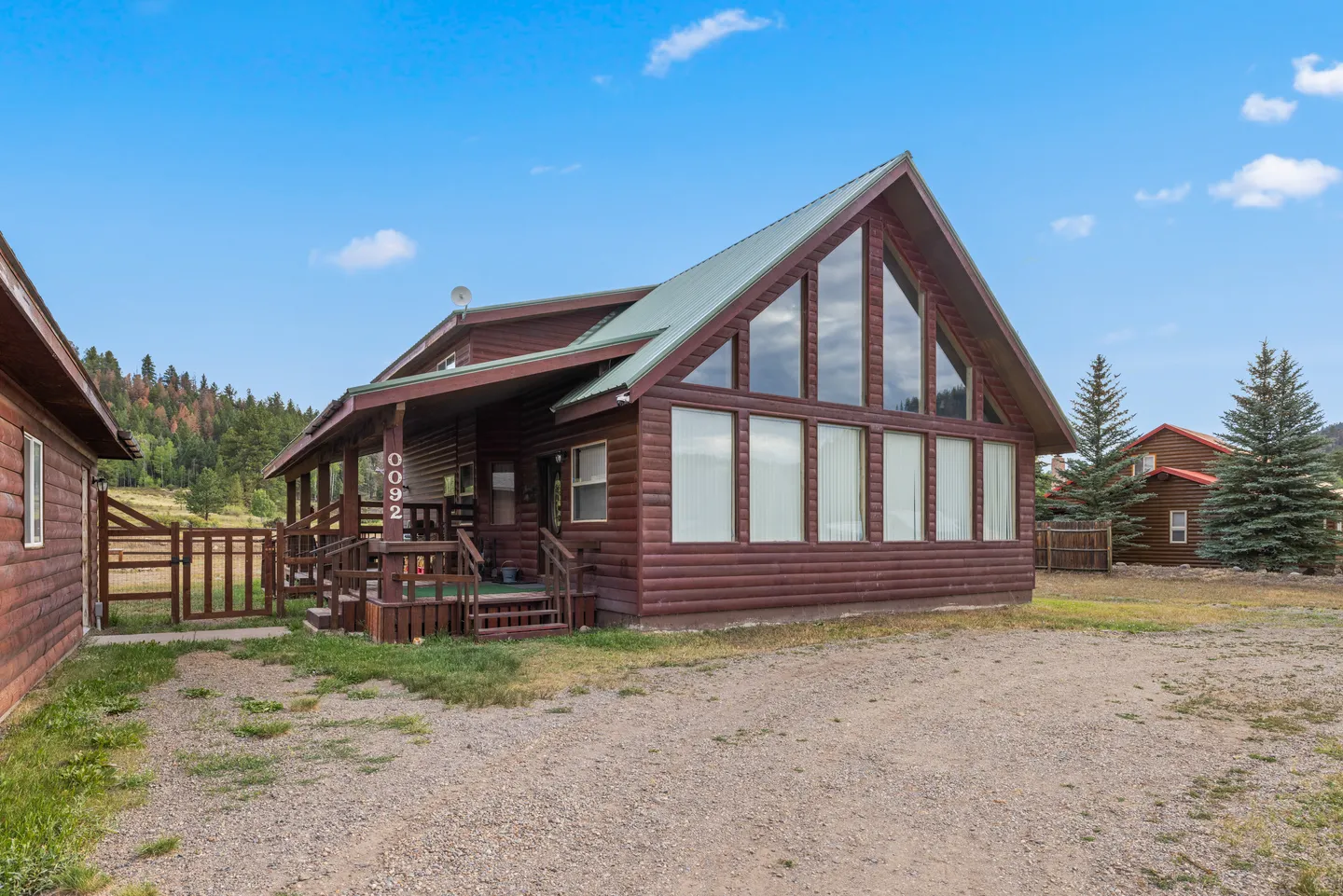 Exterior front view of a log cabin style home with large A-frame windows and a front porch.