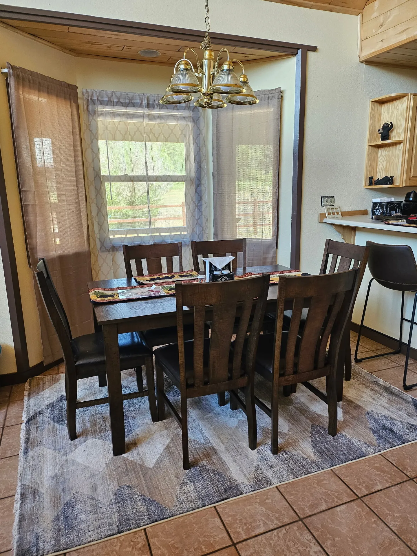Dining area featuring a dark wooden table with six matching chairs set on an area rug near a bay window.