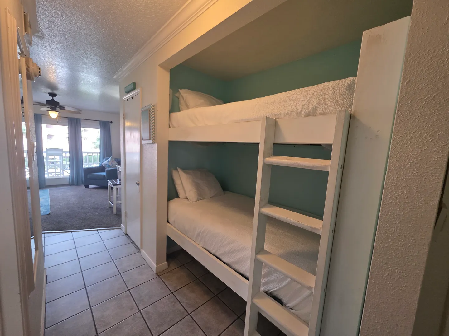 Hallway alcove with built-in white bunk beds leading towards an open living area.