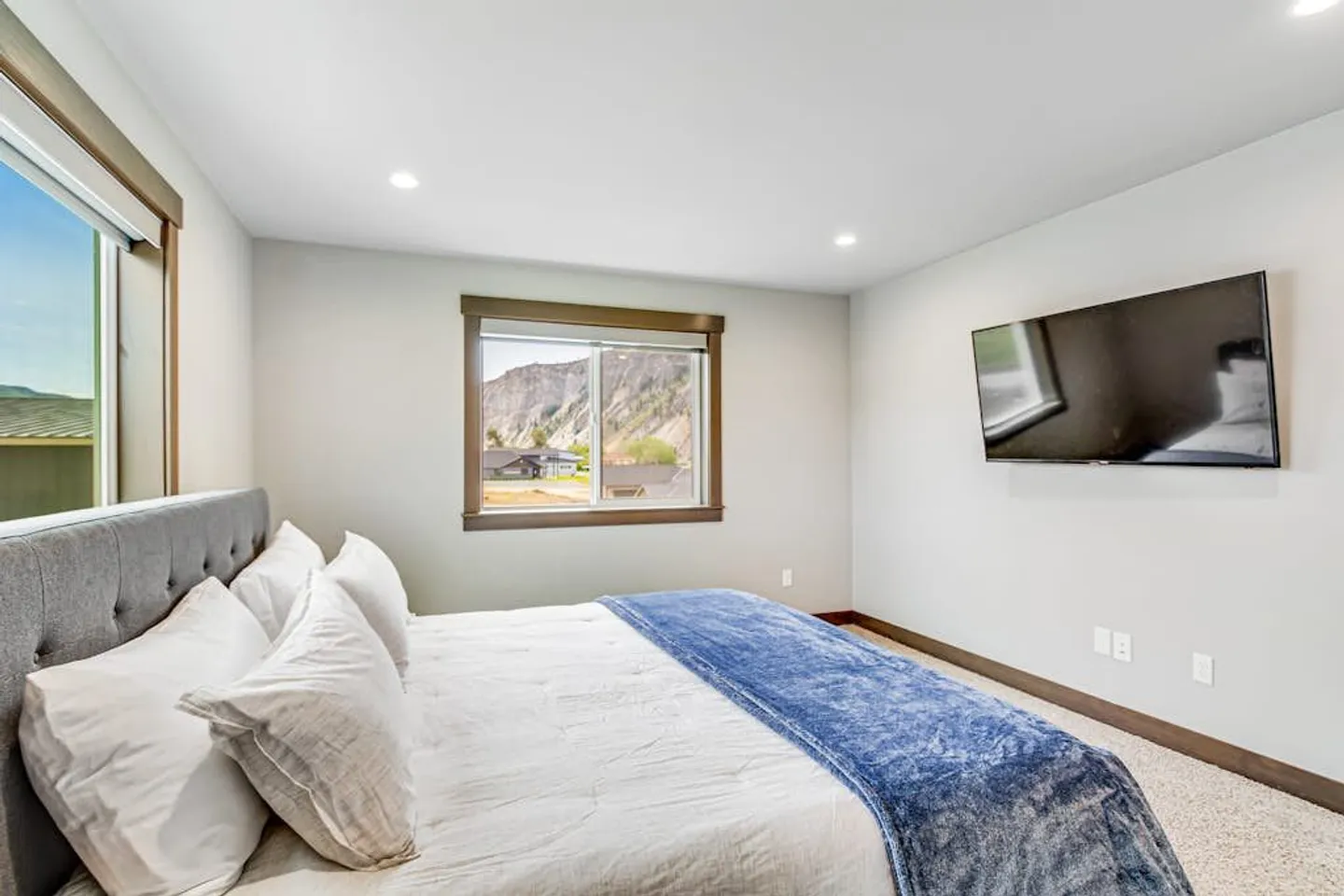 Bedroom with a made bed, wall-mounted television, and a window with mountain views.