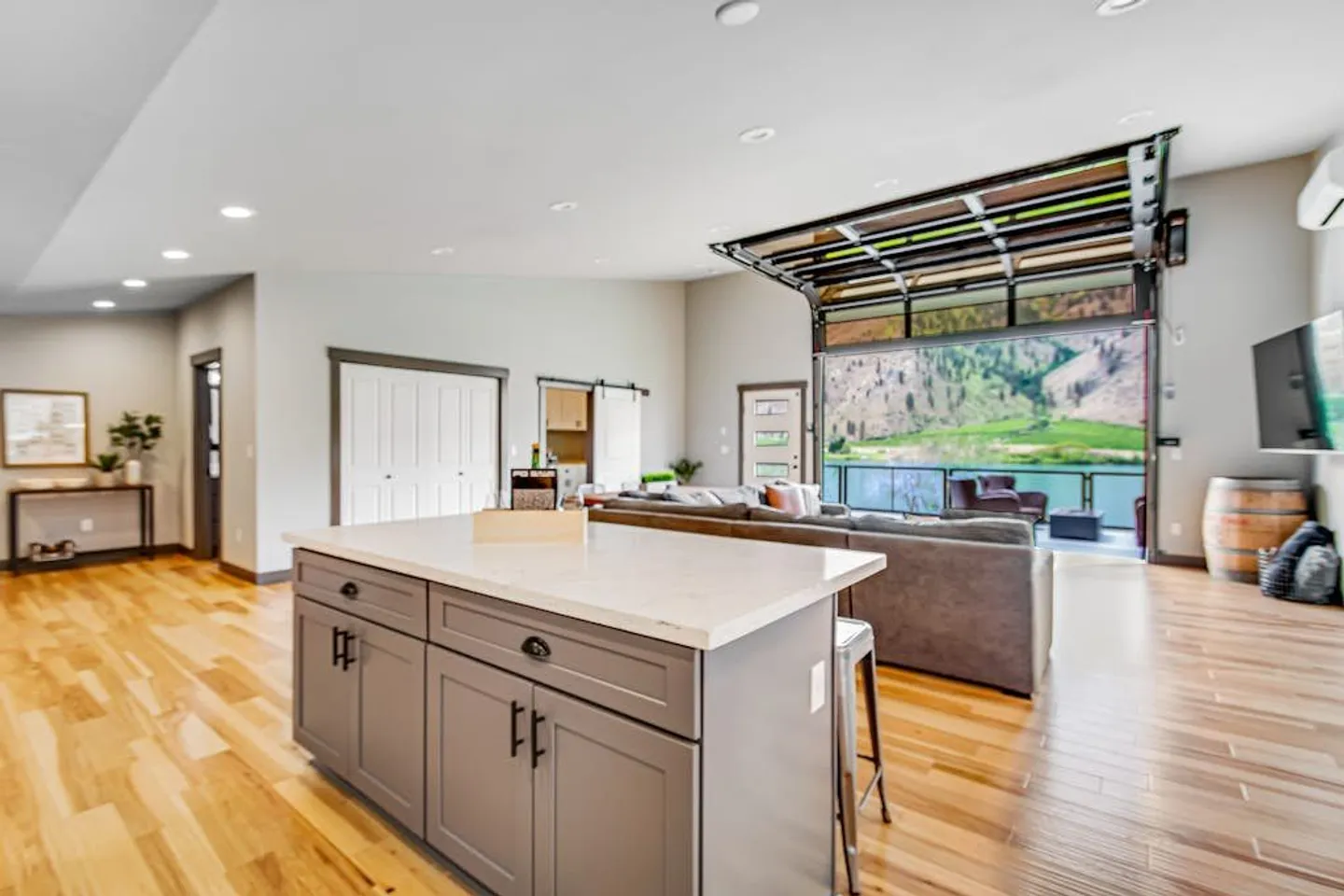 Open concept living room and kitchen featuring a large roll-up glass garage door opening to an outdoor patio with mountain views.