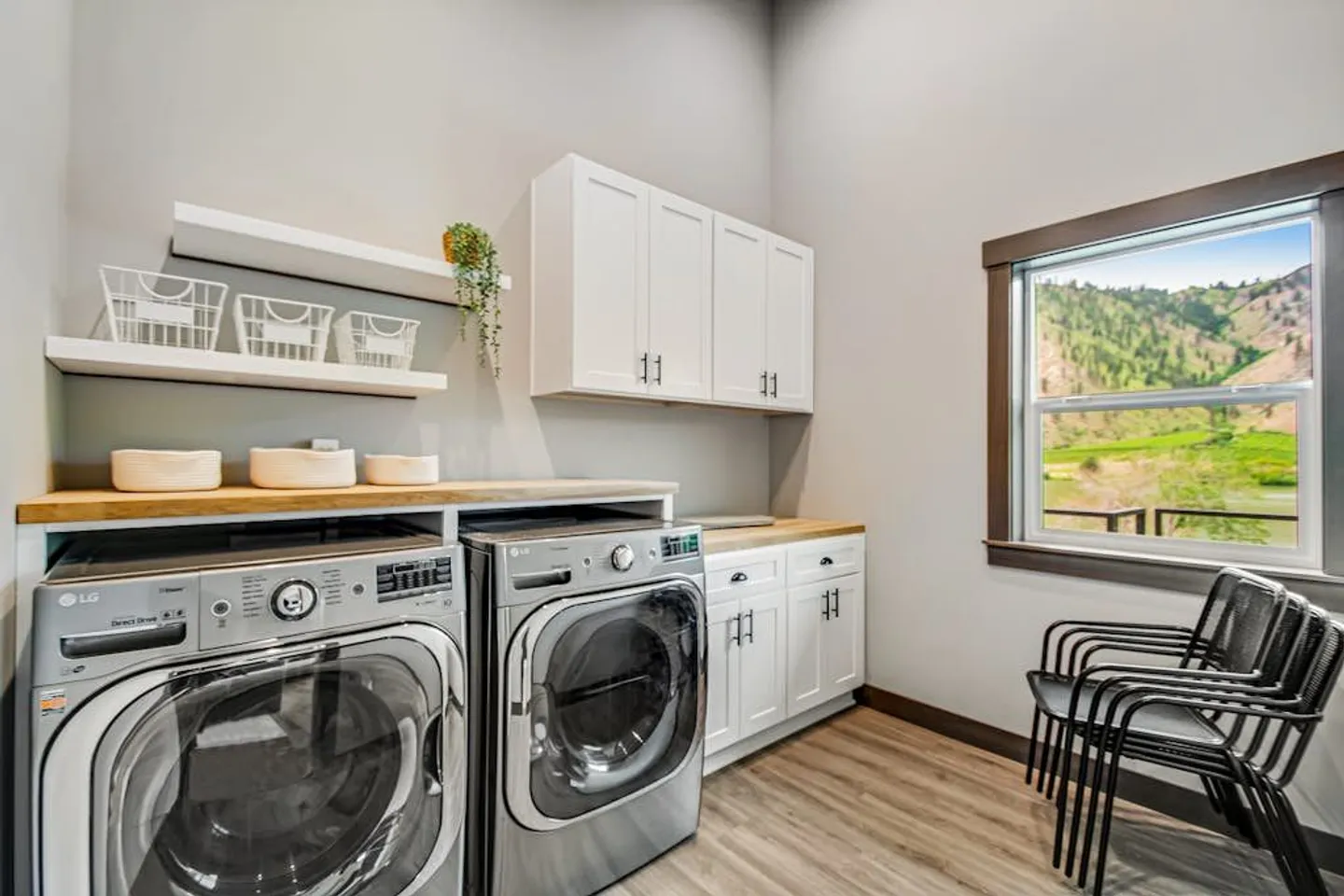 Laundry room with stainless-steel front-load washer and dryer under wood-look counters and white cabinetry.