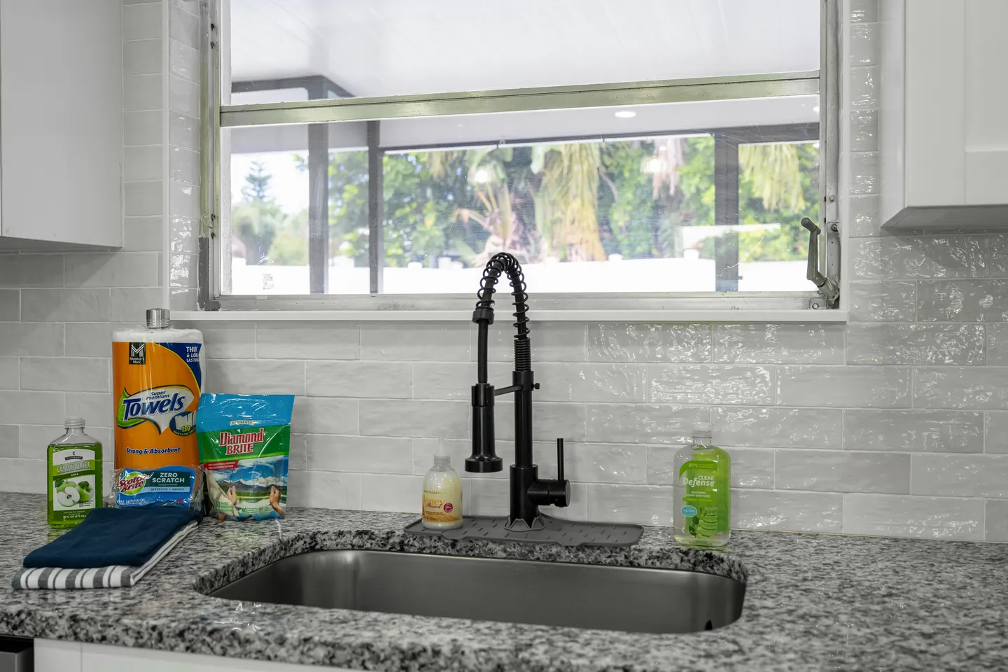 Close-up of a kitchen sink with a black pull-down faucet beneath a horizontal window.