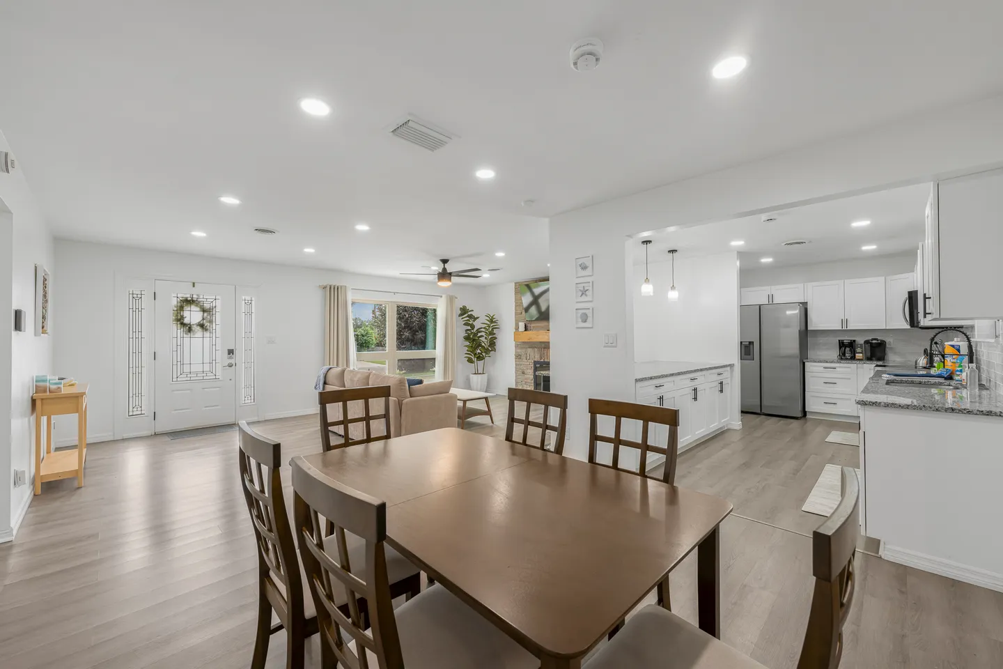 Open-concept dining area with a wooden table and chairs, leading into the living room and adjacent kitchen.