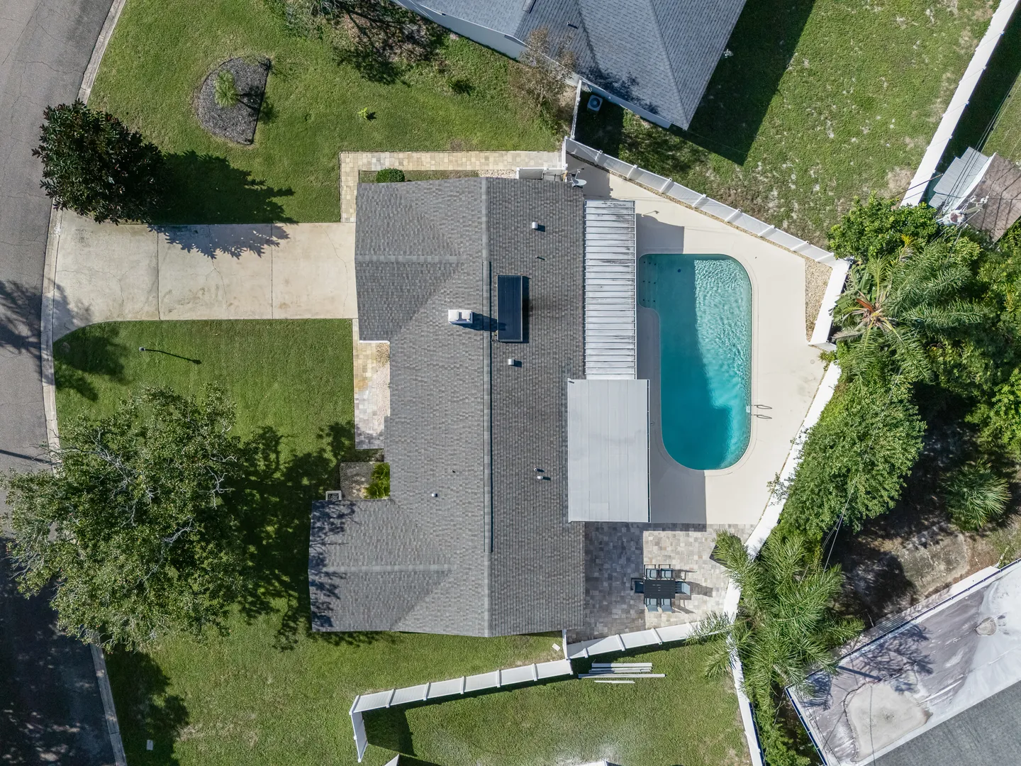 Direct overhead aerial view of a single-story home, driveway, and fenced backyard with a swimming pool and patio.