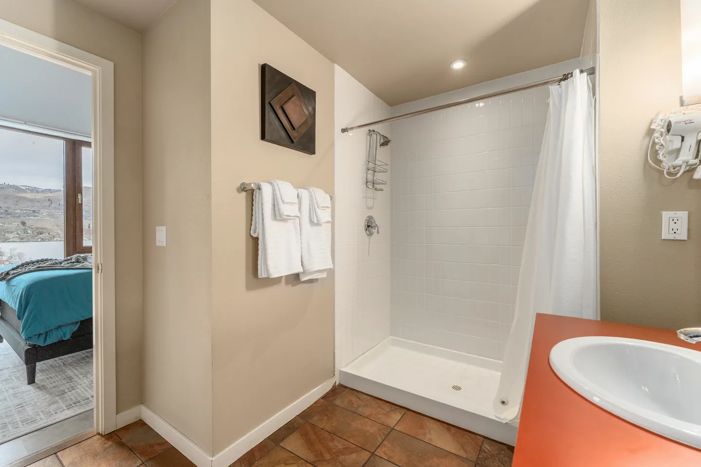 Bathroom with a walk-in shower lined with white subway tile, a white shower curtain, and a view into an adjacent bedroom.
