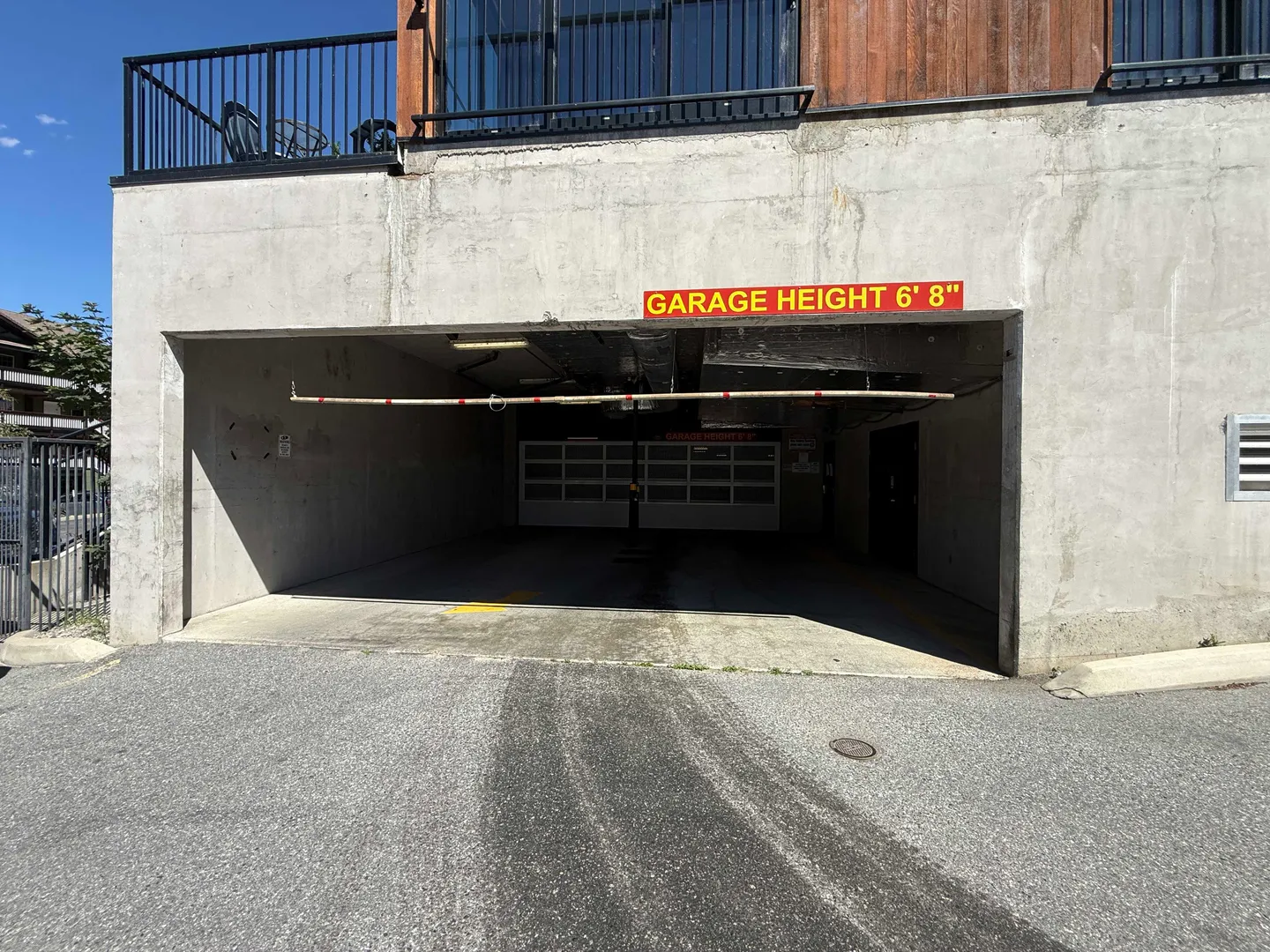 Exterior view of a concrete parking garage entrance with a sign indicating a 6 foot 8 inch clearance height.