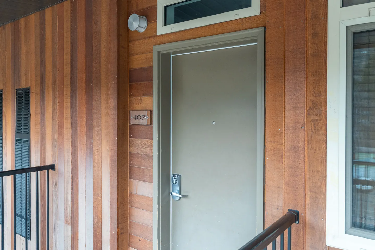 Exterior unit entry door marked 407 set into vertical wood-paneled walls.