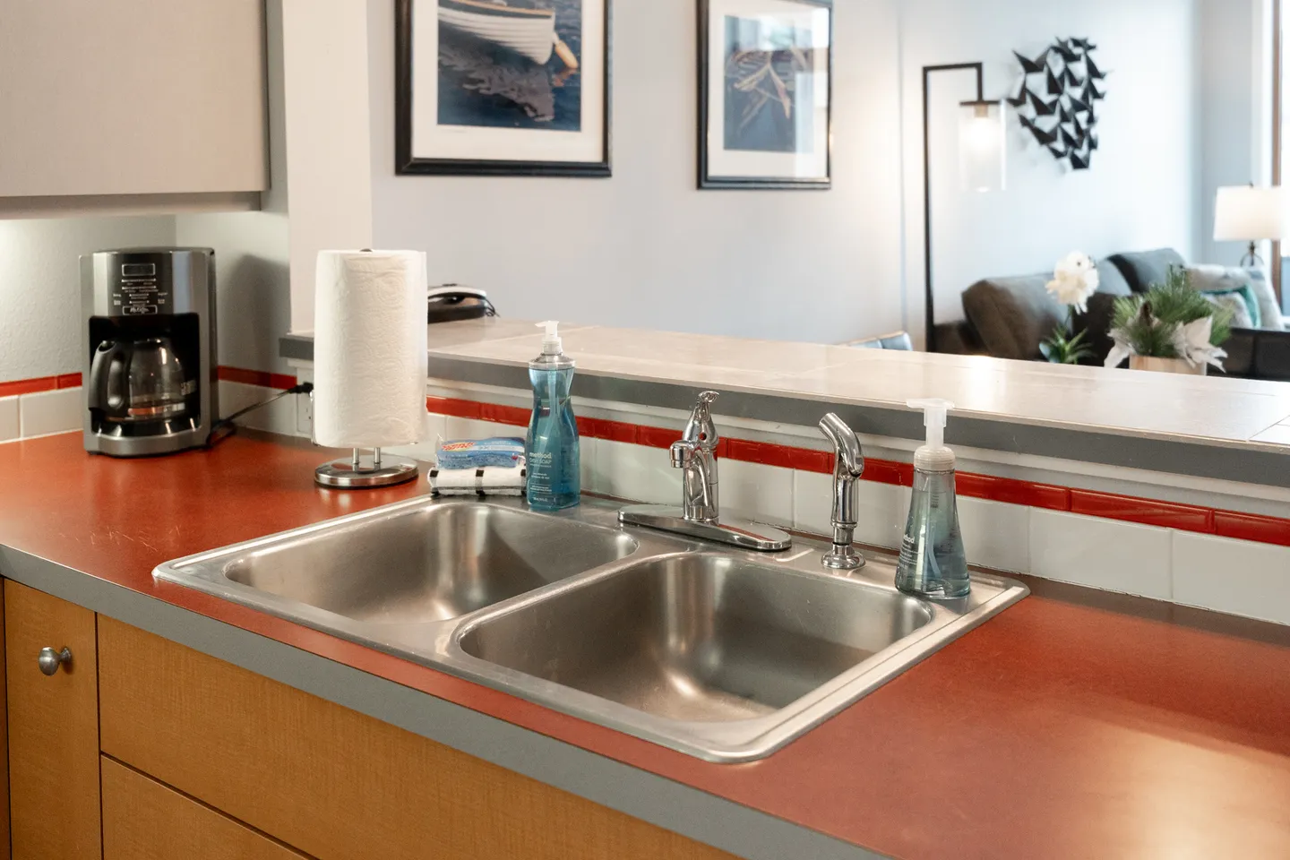 Kitchen counter with a double stainless steel sink overlooking a living room area.