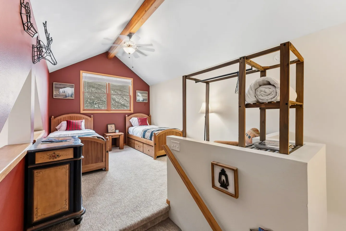 Loft bedroom with carpet, vaulted ceiling, exposed wood beam, two twin beds, and a red accent wall.