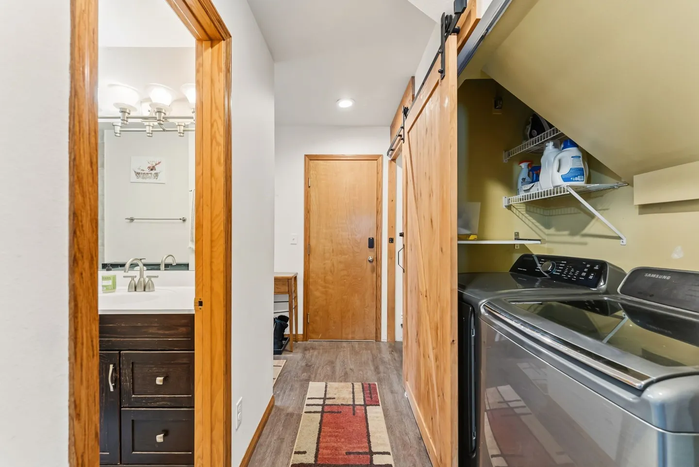 Hallway featuring a laundry nook with washer and dryer behind a sliding barn door, adjacent to an open bathroom door.