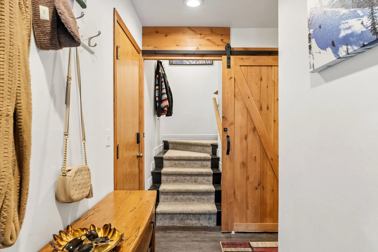 Entryway hallway with a sliding wooden barn door opening to a carpeted staircase.