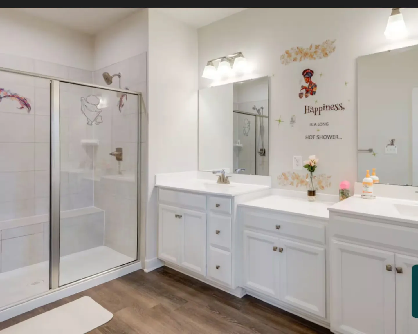 Bathroom with white double vanity cabinets and a glass-enclosed walk-in shower with tiled walls.