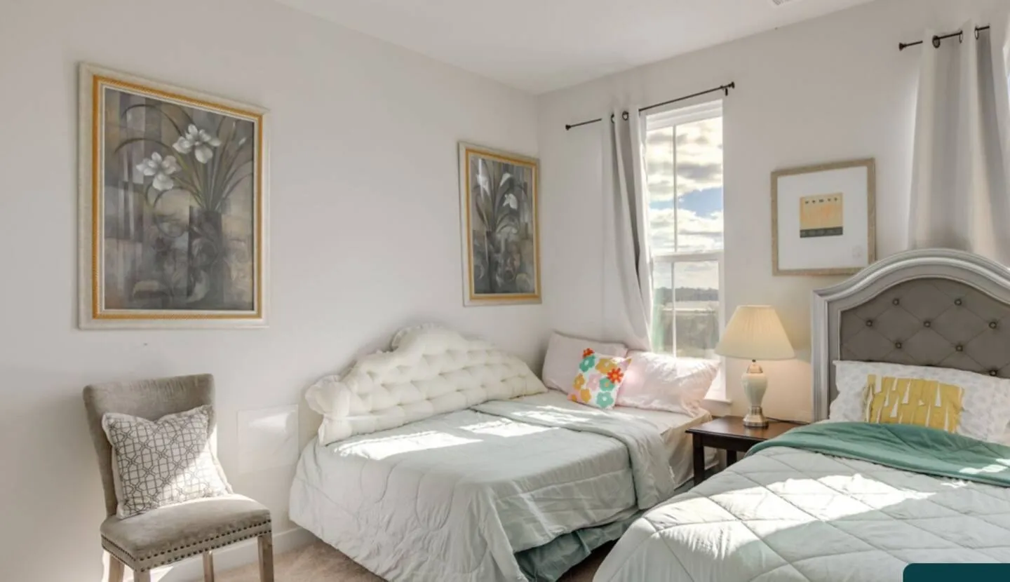 Bedroom featuring a daybed nestled near a window, a second bed with a tufted headboard, and framed wall art.