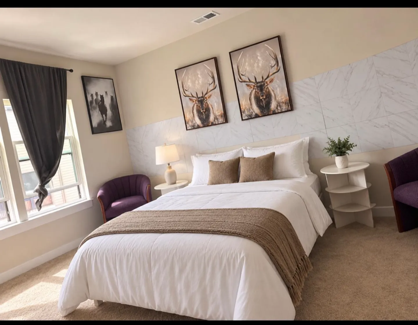 Bedroom with a made bed flanked by nightstands and purple armchairs, with framed animal art above the head of the bed.
