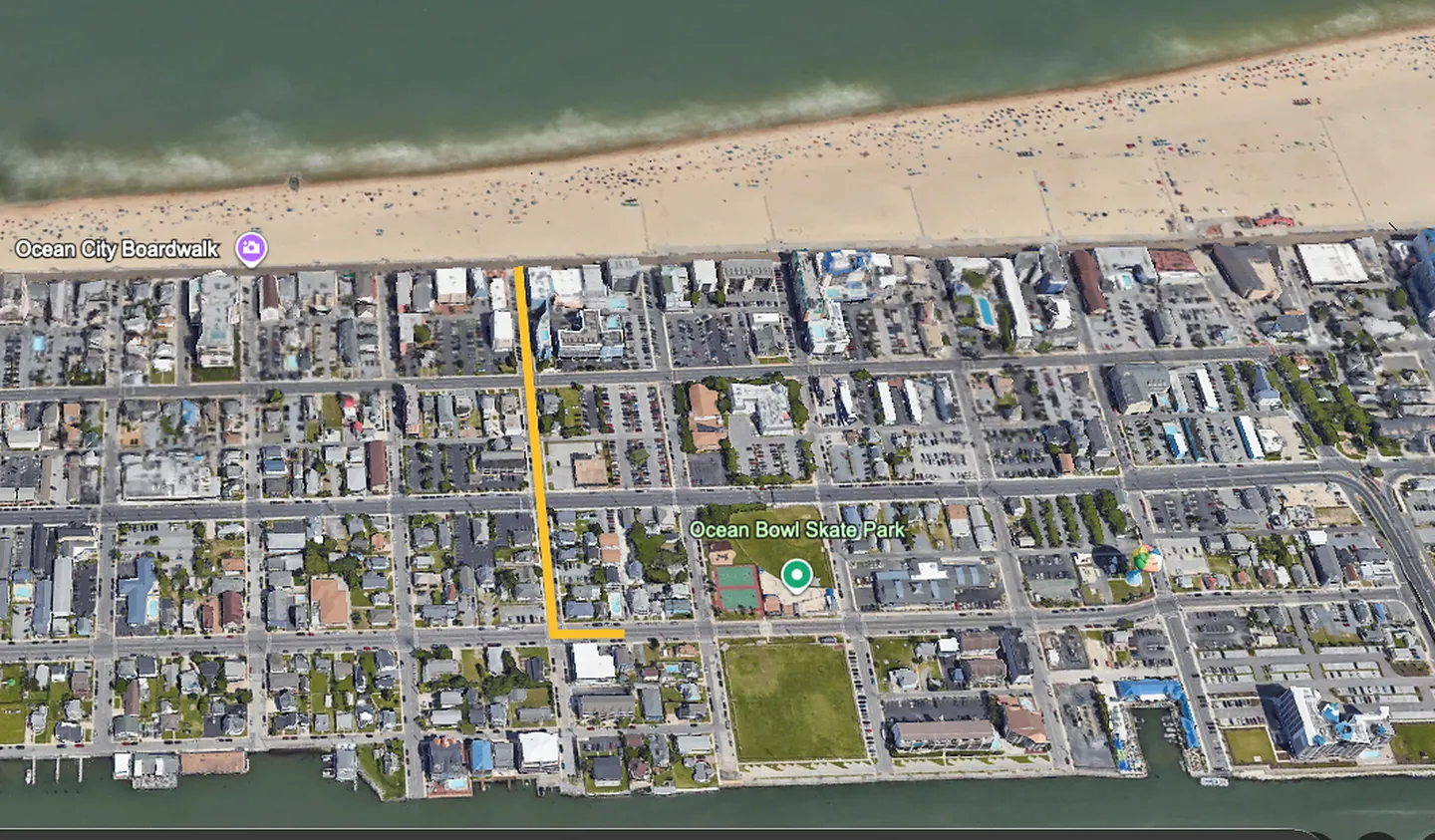 Aerial satellite map view showing city blocks leading to a sandy beach and ocean.