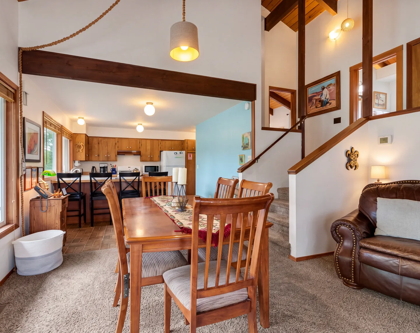 Open-concept dining and living area looking toward the kitchen and a carpeted staircase.