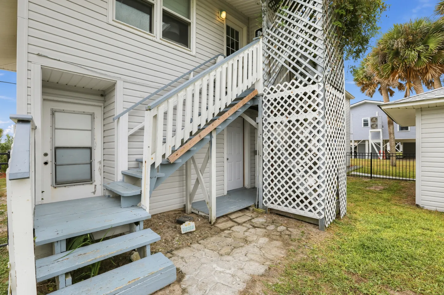 Exterior wooden staircase painted light blue and white leading to an upper entrance of a home.