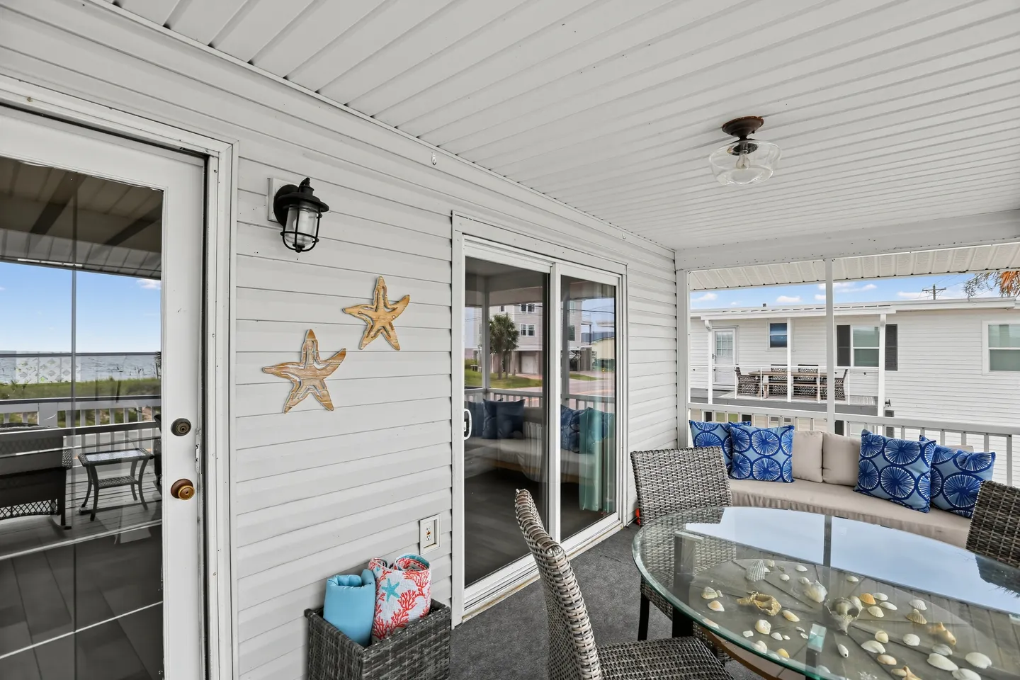 Screened porch with a glass dining table, woven chairs, a cushioned bench, and sliding glass doors leading indoors.