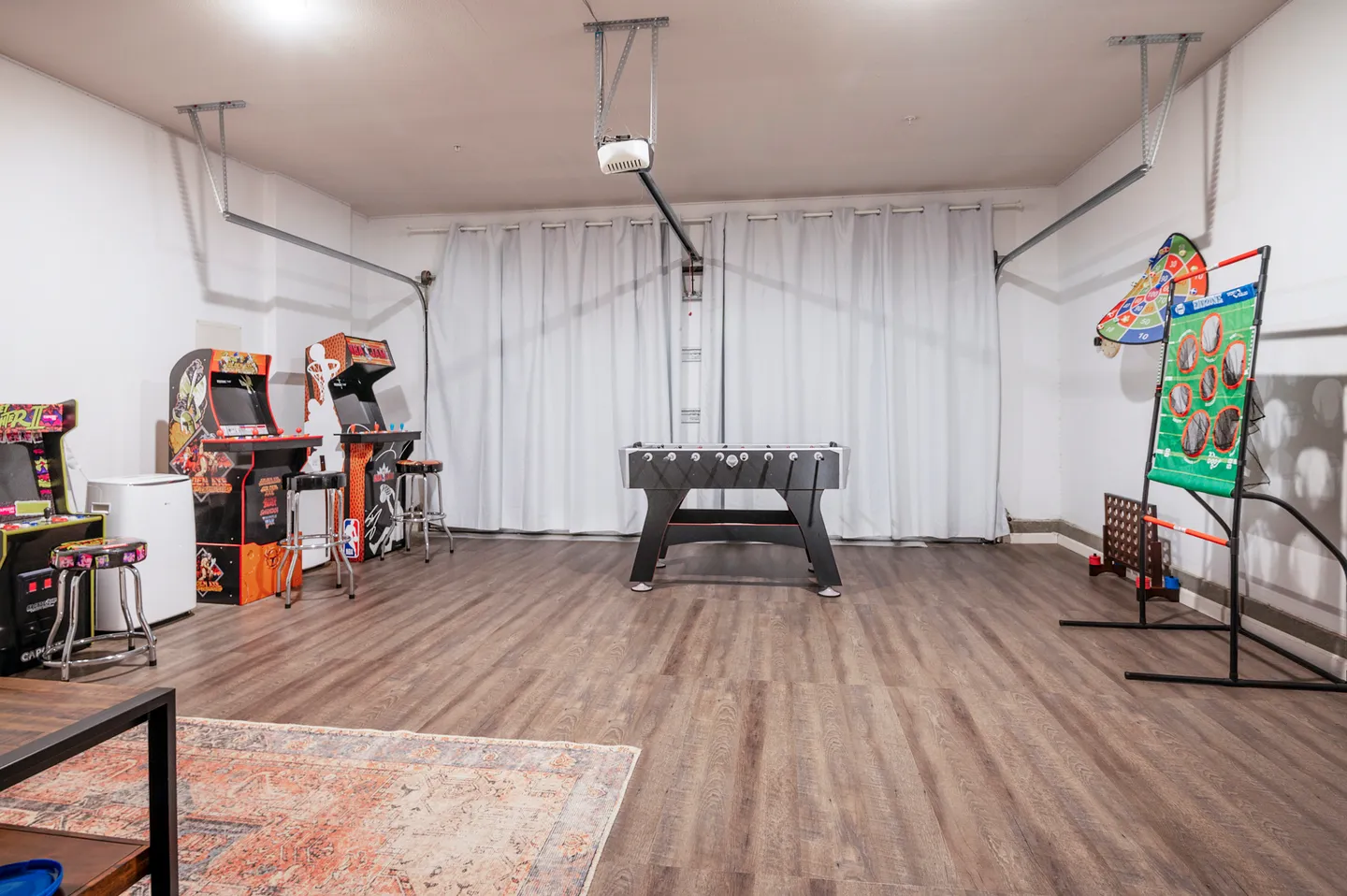 Game room setup inside a converted garage with arcade cabinets, a foosball table, and various games.