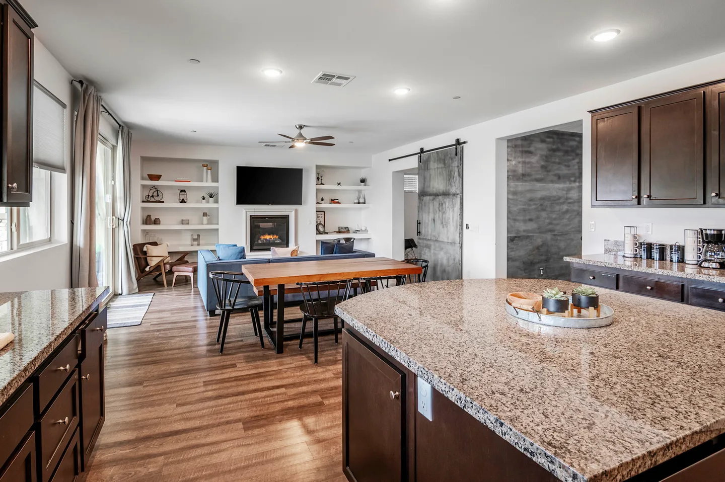 Open-concept interior showing a kitchen island in the foreground with a dining table and living room in the background.