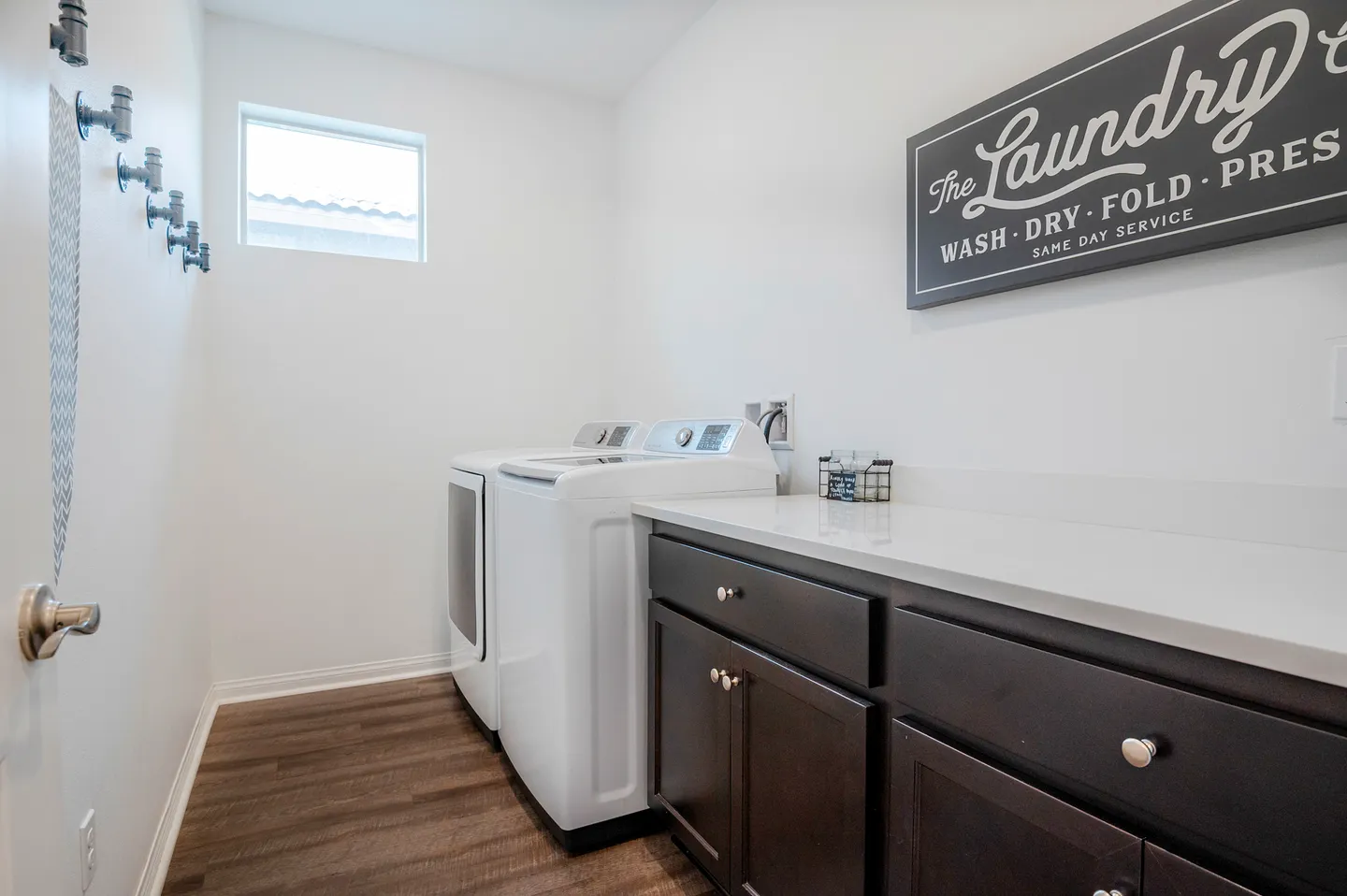 A laundry room with dark cabinetry, white countertops, and a white washer and dryer set.