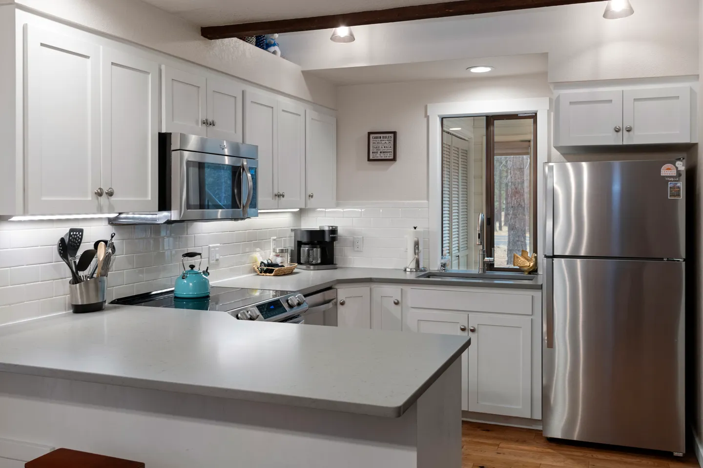 Kitchen with white cabinetry, light countertops, subway tile backsplash, and stainless steel appliances.