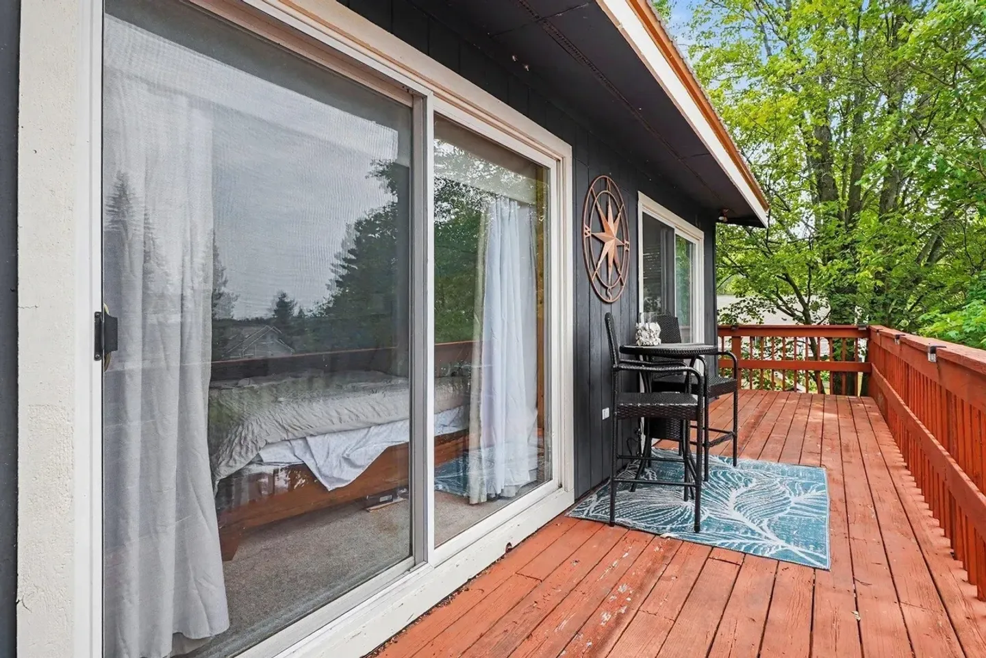 Outdoor wooden deck with a small patio dining set outside large sliding glass doors.