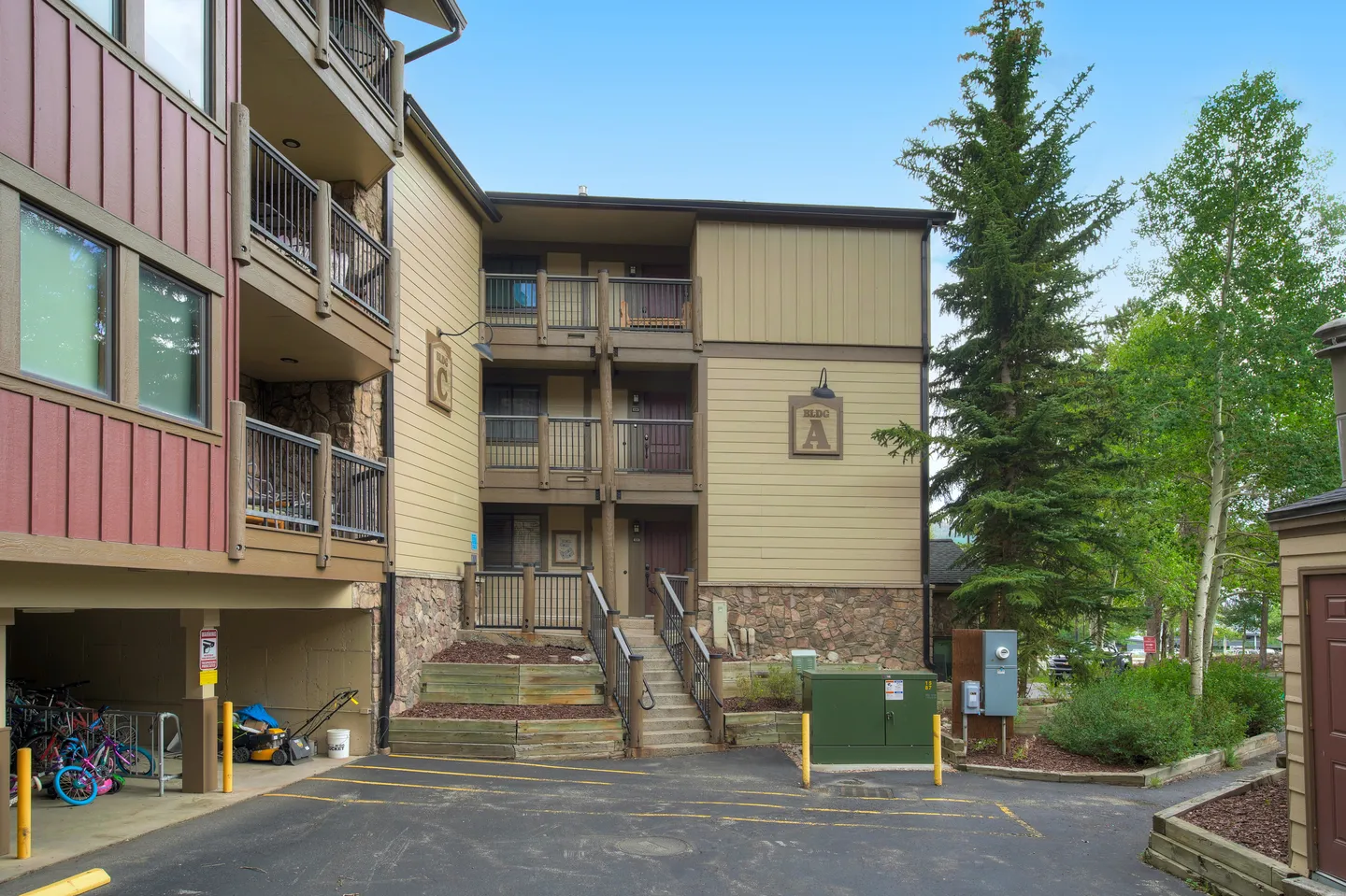 Exterior of multi-story apartment complex labeled Building A with covered parking, exterior stairs, and balconies.