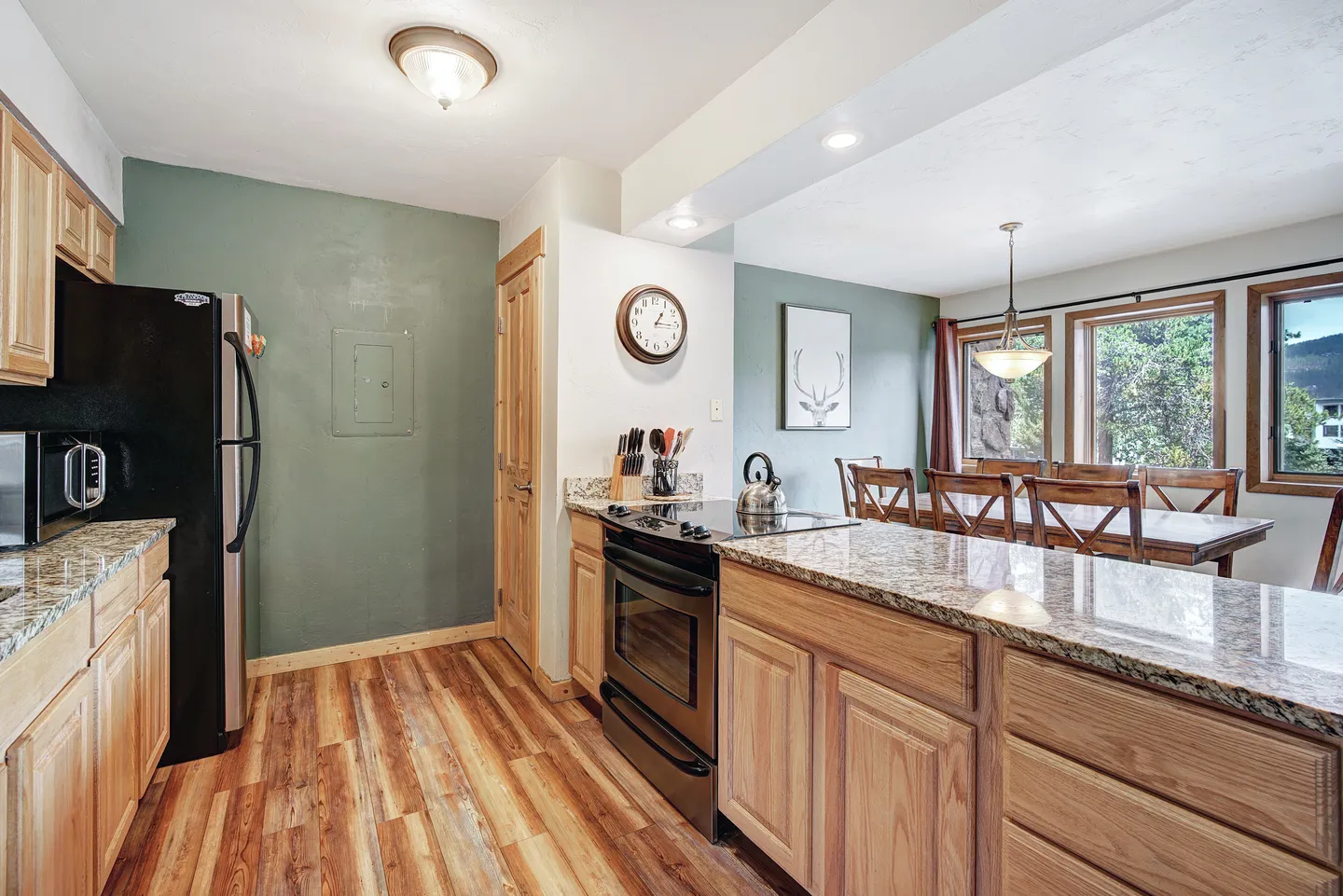 Kitchen with light wood cabinets, granite countertops, and an electric range looking into the adjacent dining area.
