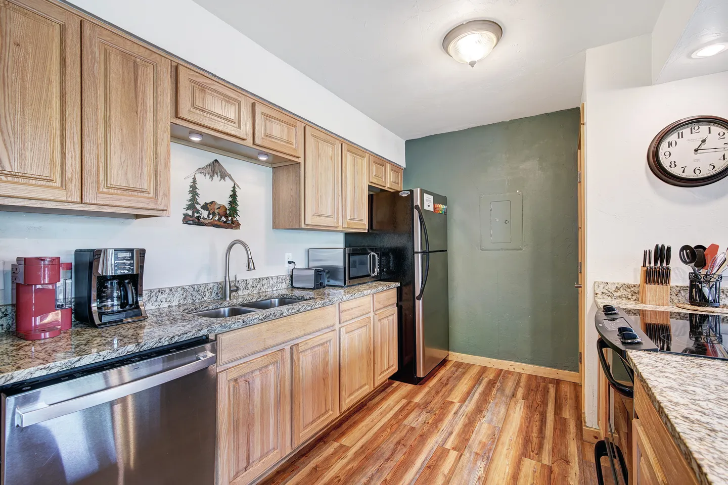 Kitchen with light wood cabinetry, speckled countertops, stainless steel appliances, and wood-look flooring.
