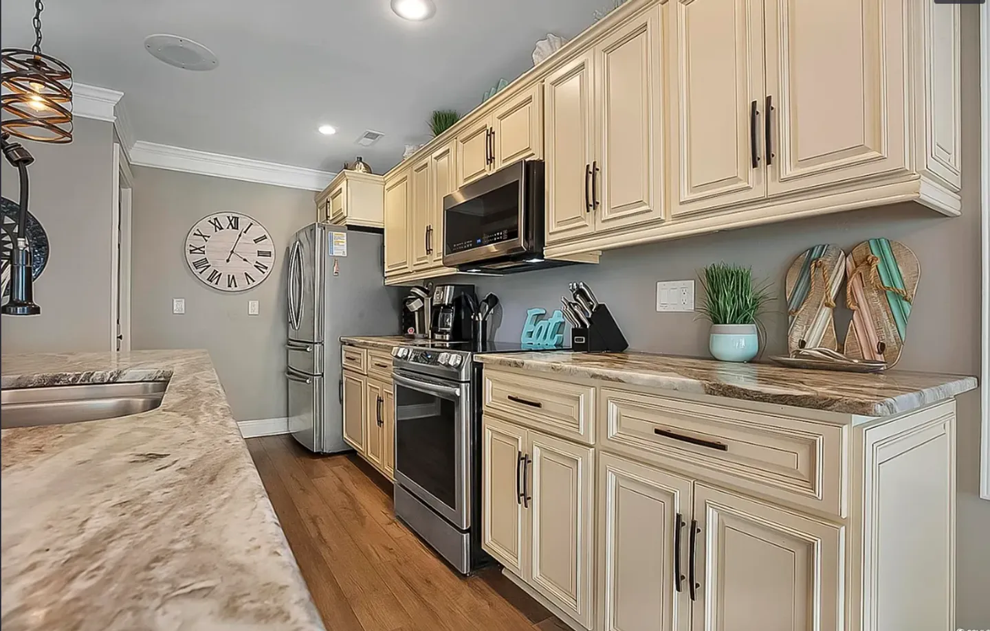 Kitchen with cream-colored raised-panel cabinets, stone-look countertops, and stainless steel appliances.