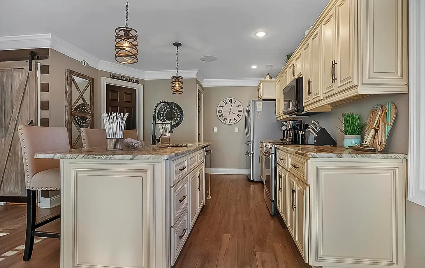 Kitchen with an island, wood-look flooring, cream-colored cabinetry, and stainless steel appliances.