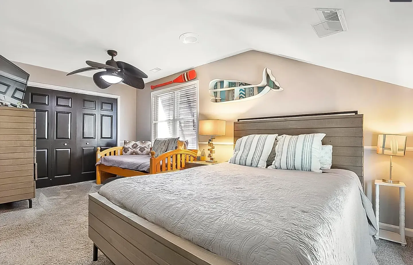 Bedroom with a bed, daybed, ceiling fan, and nautical-themed wall decor.