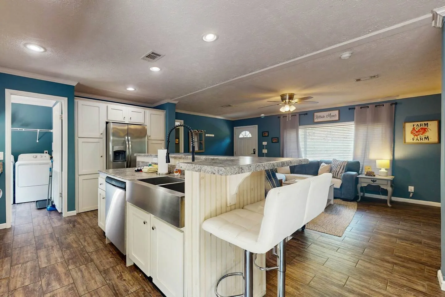Open concept kitchen with two-tier island and stainless steel appliances looking toward the living room.