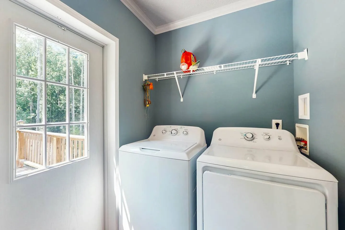 A laundry room with blue walls, a white washing machine, a white dryer, and an exterior door with a window.