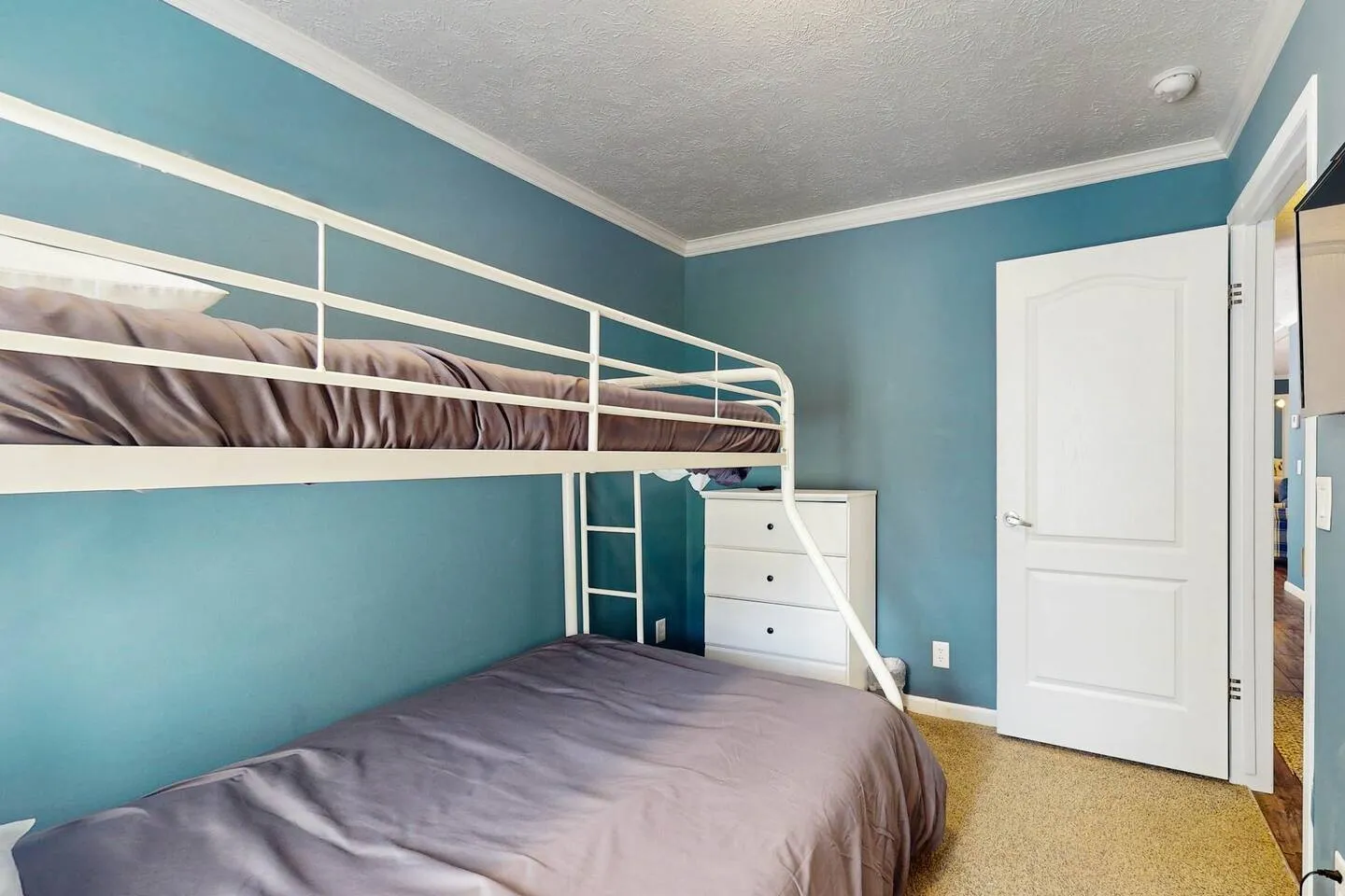 Bedroom featuring blue walls, carpeted flooring, and a white metal bunk bed.