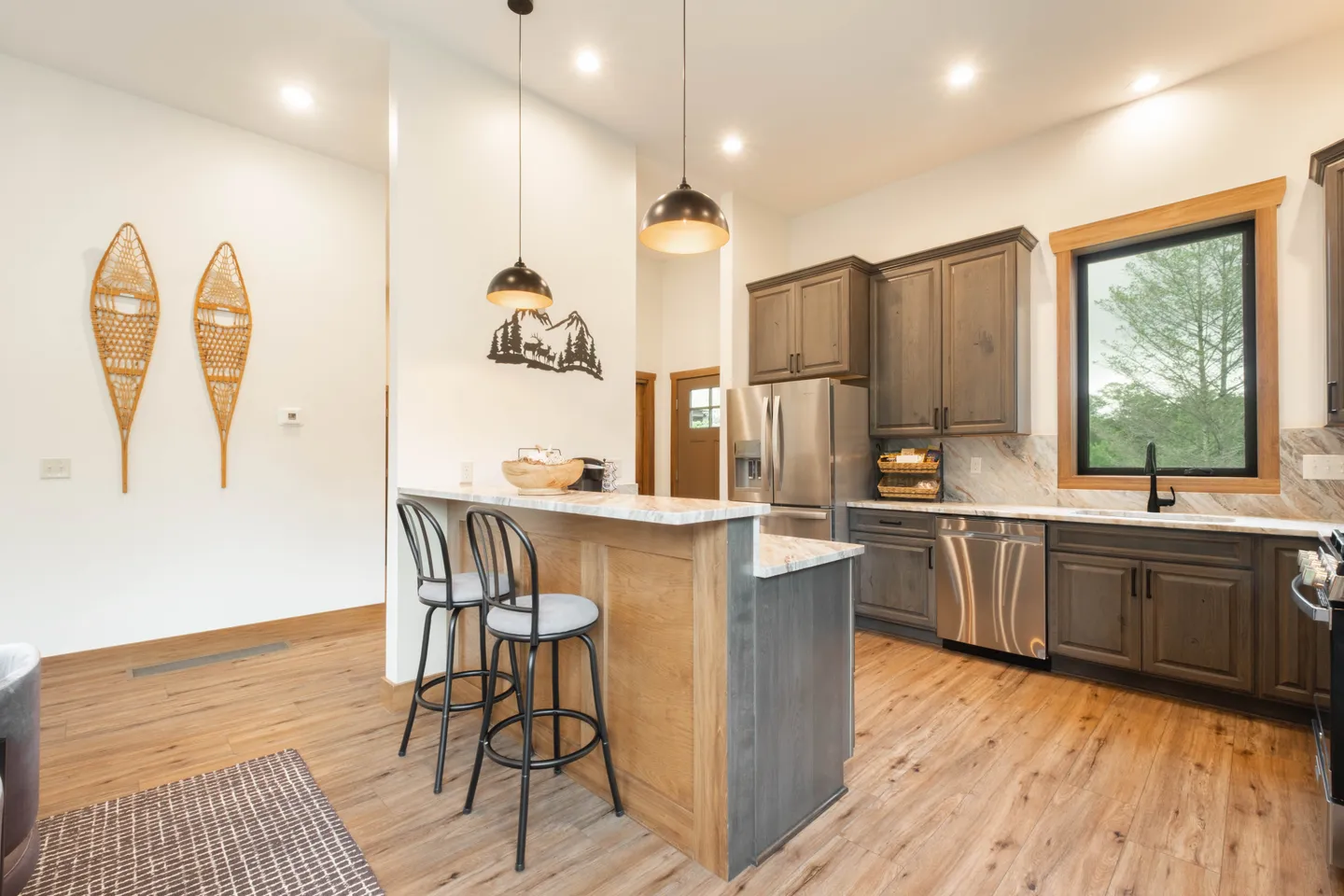 Kitchen with wood-look flooring, stainless steel appliances, dark wood cabinets, and an island with bar stools.