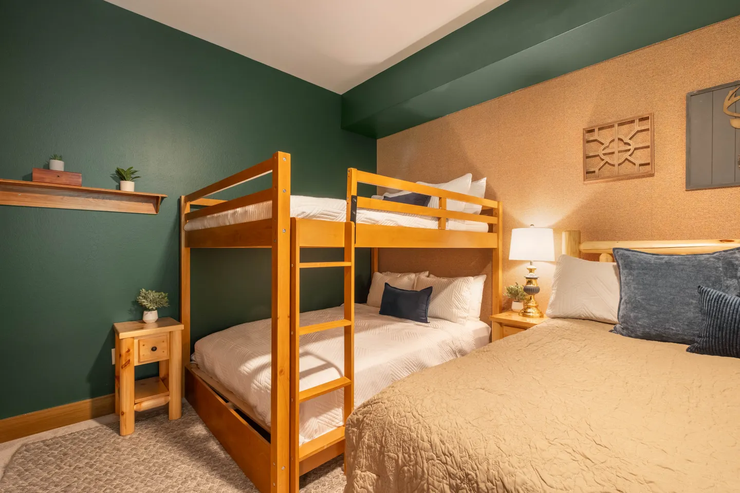 Bedroom featuring a wooden bunk bed, an adjacent regular bed, nightstands with a lamp, and a green accent wall.