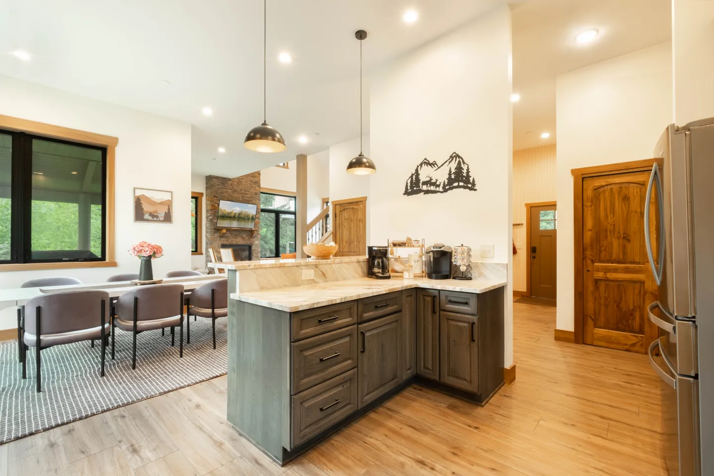 Open concept kitchen island and coffee station looking into the dining area and living room with a fireplace.