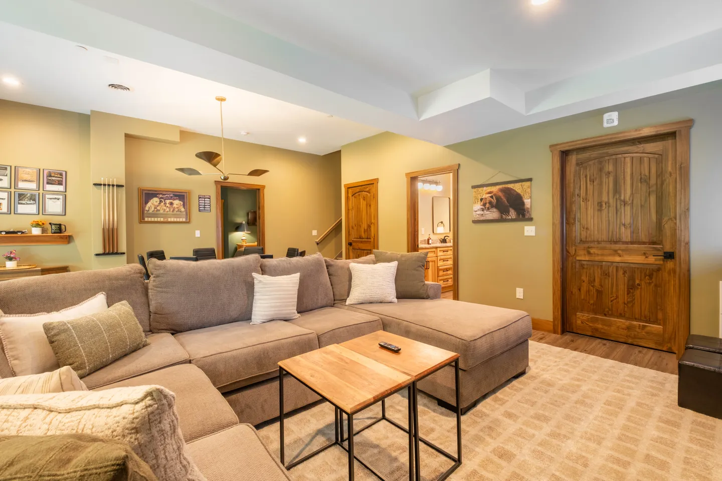 Living area with a large grey sectional sofa, nesting coffee tables, an area rug, and doorways leading to other rooms.