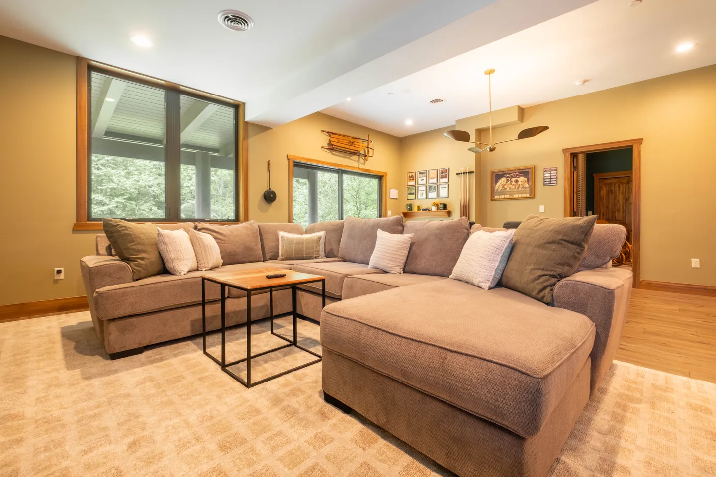 Living area featuring a large plush sectional sofa with throw pillows, a small wood and metal coffee table, and an area rug.
